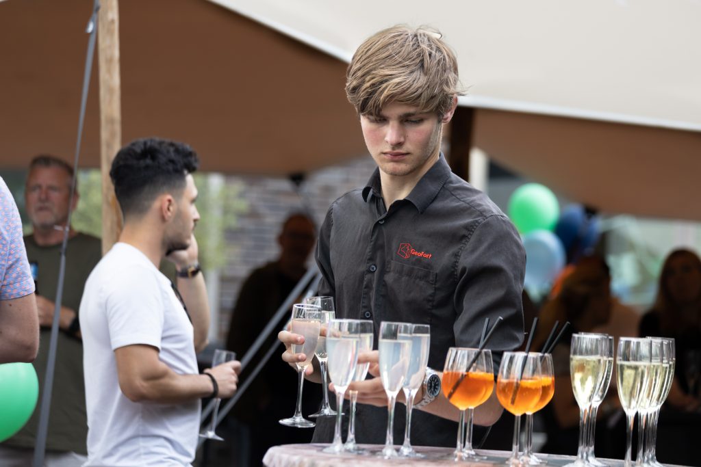 Bediening bij GeoFort Culinair serveert champagne glazen uit